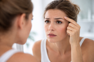 אישה מביטה בדאגה בקעקוע הגבות שלה שהשתנה עם הזמן